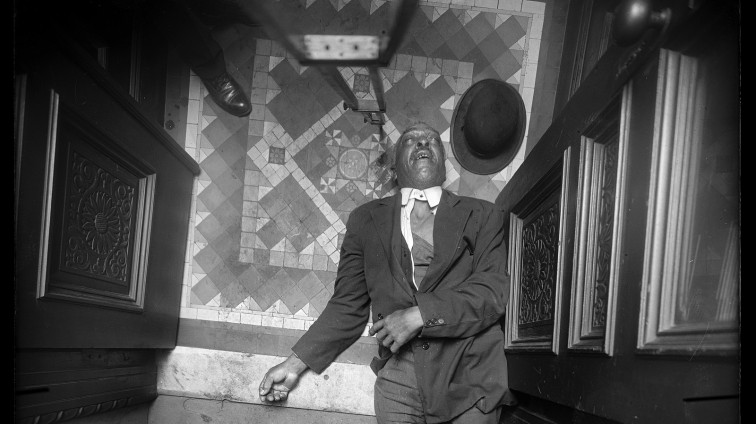 Dead Black man on the floor in New York City in the early 20th century. 